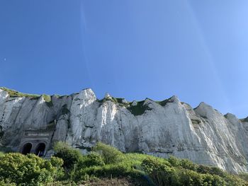 Low angle view of rocks against clear blue sky