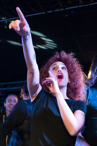 Portrait of young woman with arms raised