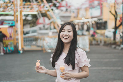 Portrait of smiling young woman holding bubble wand at amusement park