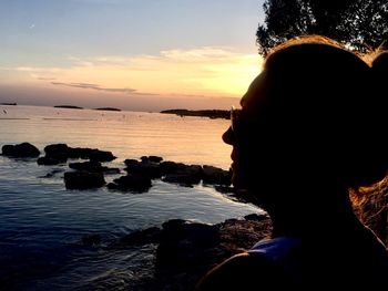 Close-up of silhouette woman at beach against sky during sunset