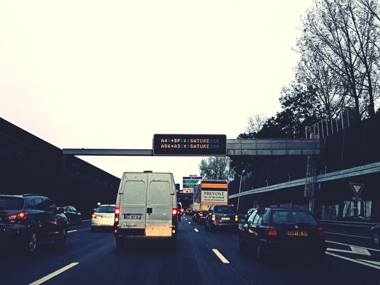 transportation, car, land vehicle, mode of transport, road, clear sky, street, text, traffic, on the move, western script, communication, road marking, copy space, city, travel, road sign, tree, city street, vehicle