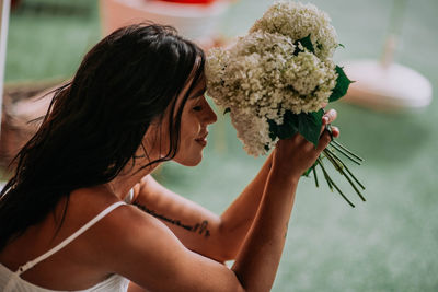 Side view of woman holding red flowering plant