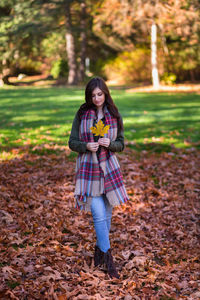 Full length portrait of smiling woman standing on land