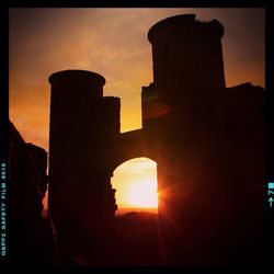 Low angle view of silhouette built structure against sky at sunset