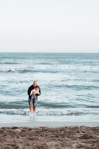 Man with daughter standing on shore at beach