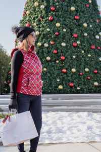 Woman standing by christmas tree