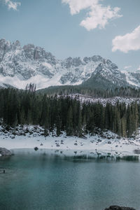 Scenic view of lake by snowcapped mountains against sky