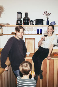 Happy family enjoying food and drinks in kitchen at home