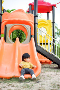 Rear view of woman sitting on slide at park