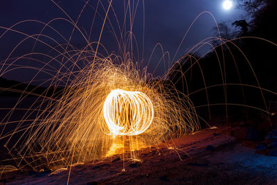 Spinning wire wool against sky at night