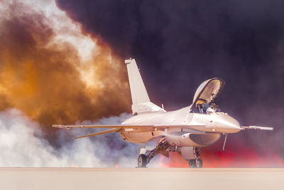 Fighter airplane on runway against sky