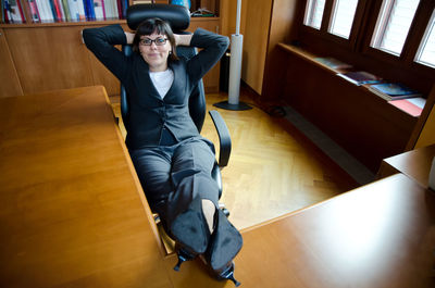 Portrait of happy businesswoman relaxing on chair in office