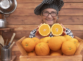 Smiling senor woman holding oranges