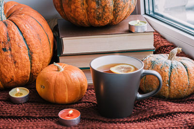 Cozy autumn still life. books, pumpkins and cup of hot coffee on windowsill with knitted scarf.