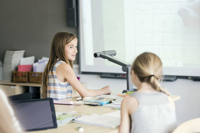 School girls sitting by desk in classroom