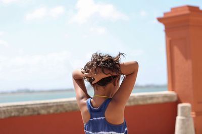 Young girl standing against sea against sky