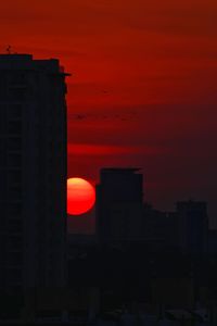 Silhouette buildings against orange sky