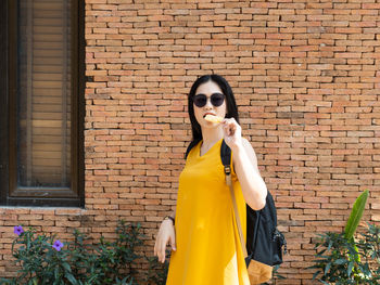 Young woman standing against brick wall