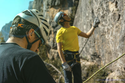 Hikers climbing rock formation on sunny day