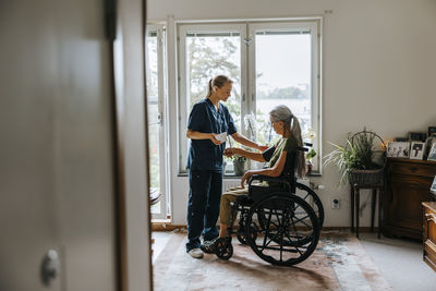 Female medical expert checking blood pressure of elderly woman with disability at nursing home