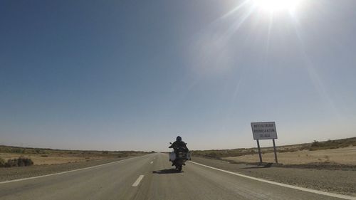 Man riding motorcycle on road against sky