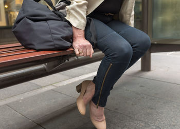 Low section of woman sitting on footpath