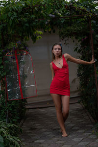 Portrait of young woman in red dress standing in garden 