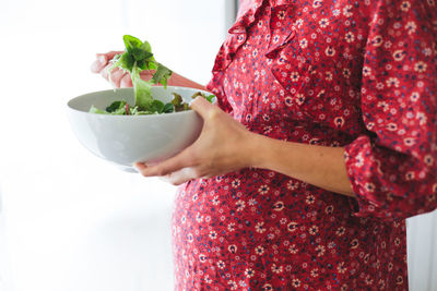 Midsection of woman holding strawberries in bowl