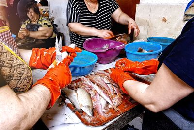 Midsection of people holding fish at market
