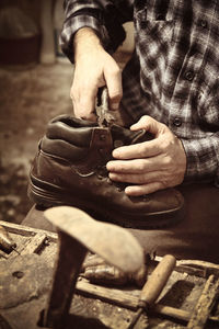 Midsection of male shoemaker making shoe in workshop