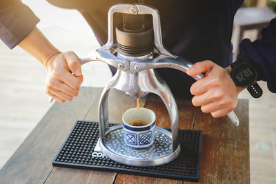 Close-up of hand pouring coffee cup on table