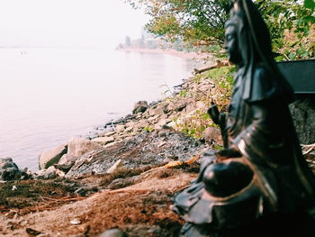 Close-up of statue by rock against sky