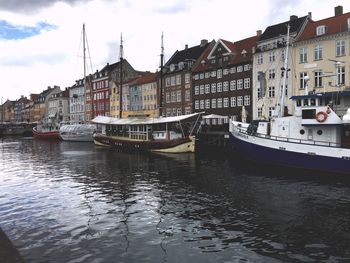 View of buildings at waterfront against cloudy sky