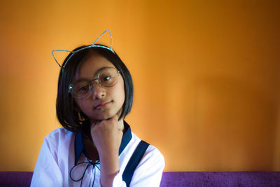 Portrait of girl with hand on chin sitting at home