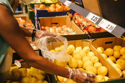 Midsection of woman holding fruits for sale at market stall