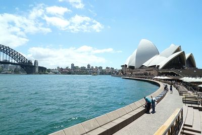 City at waterfront against cloudy sky