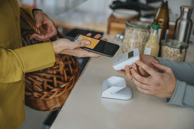 Store clerk holding bar code scanner for female customer while making contactless payment in retail store