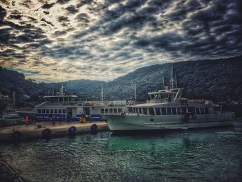 Boats in river against cloudy sky