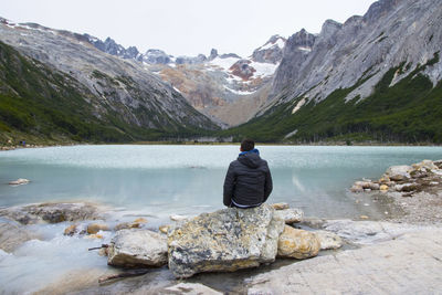 Rear view of man looking at lake against mountain