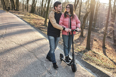 Loving young millennials having fun walking on an electric scooter