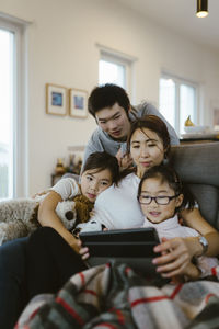 Mother and children watching digital tablet while sitting on sofa at home