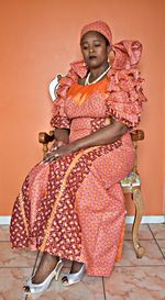 Woman in traditional clothing sitting on chair at home