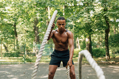 Full length of shirtless athlete exercising on footpath