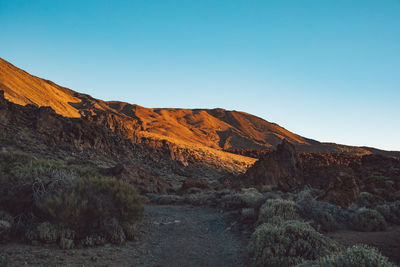 Scenic view of rocky mountains against clear blue sky at sunset 