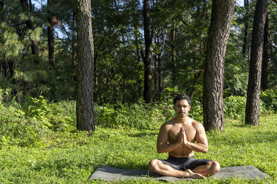 Young man practicing yoga asana, balance, meditating while standing on one leg on sports mat 