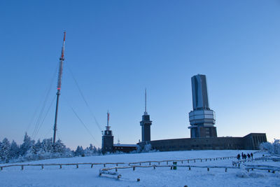 Tower on snow covered field against clear blue sky