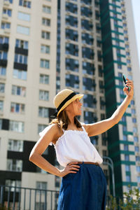 Midsection of woman photographing with mobile phone in city