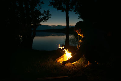 The silhouette of a girl by the fire on the lake. advertising of tourist companies and fishing. 