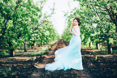 Young woman standing by trees in garden