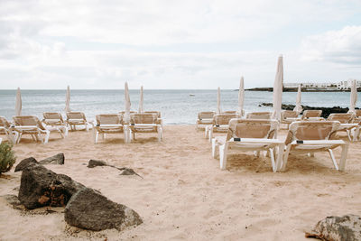 Chairs on beach against sky